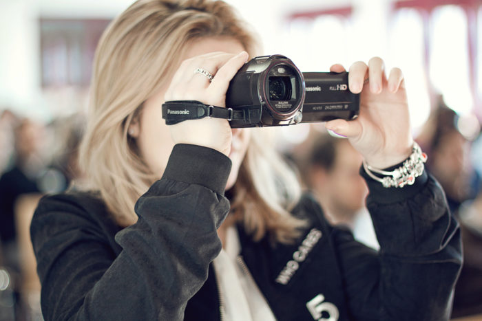 Das Foto zeigt ein weibliches JU-Mitglied, das eine Videokamera hält und eine Aufnahme macht